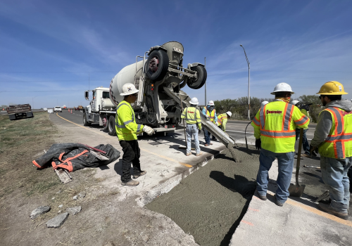 On-road construction crew laying concrete on highway